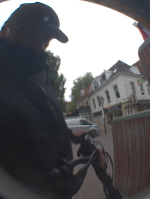 Man met pet op en fiets in de hand