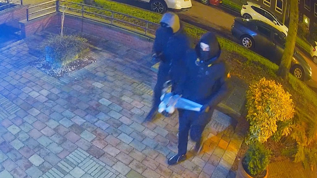 twee verdachten, donker gekleed in voortuin