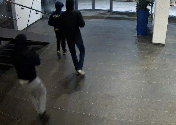 3 mannen lopen in de hal van complex