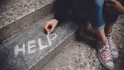 Vrouw schrijft met krijt 'help' op traptrede