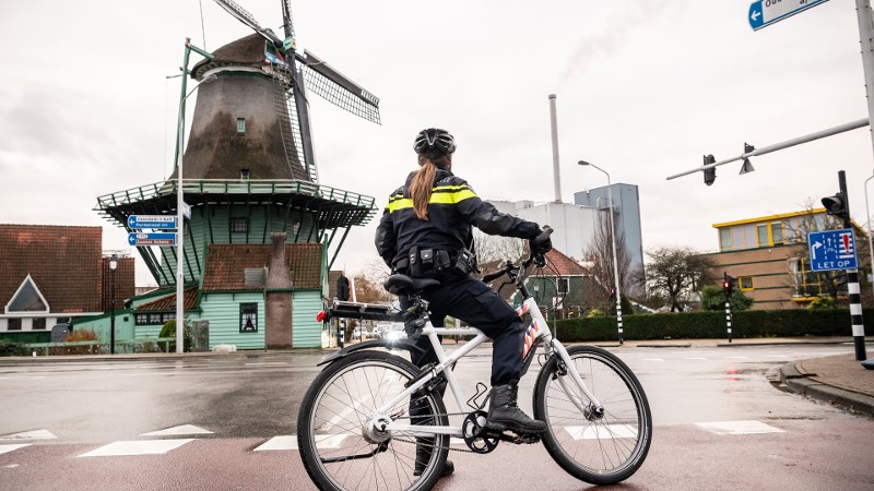 Archieffoto: een agent op de fiets bij een kruispunt, met op de achtergrond een molen.