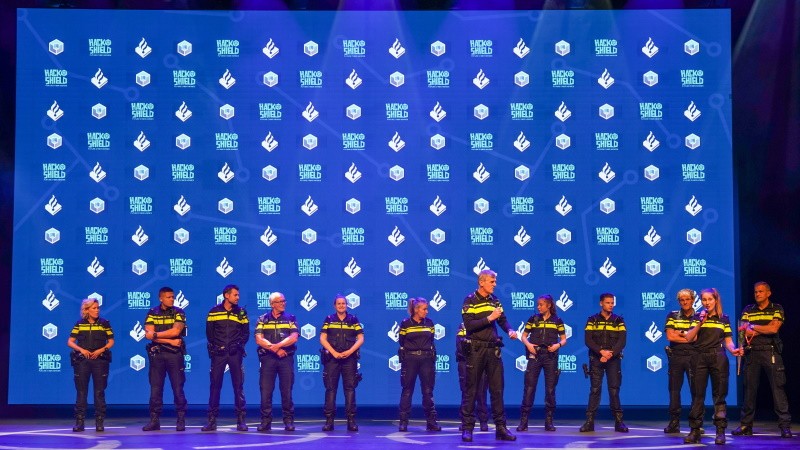 Hackshield event podium met daarop politiemedewerkers in operationeel uniform