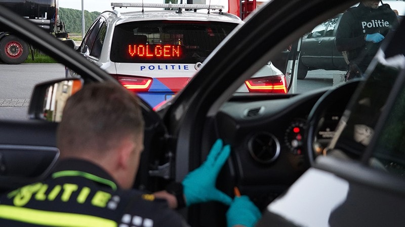 Internationale samenwerkingsactie tegen drugstransporten: ‘Etoile’- Een politievoertuig met volgteken en op de voorgrond een agent die een voertuig van binnen onderzoekt.