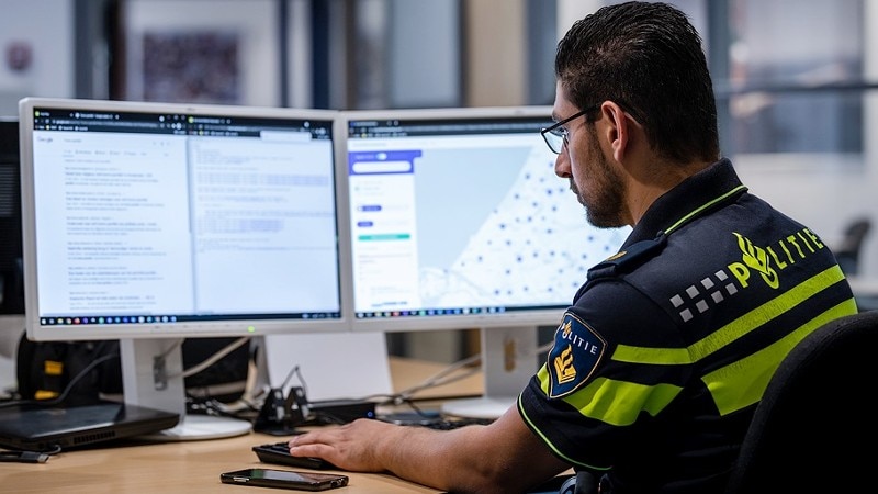 Politiemedewerker achter twee beeldschermen