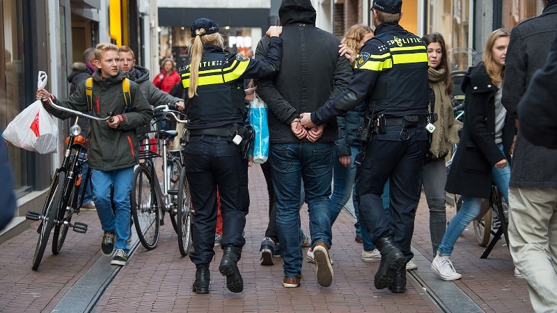 Arrestant wordt meegenomen door agenten