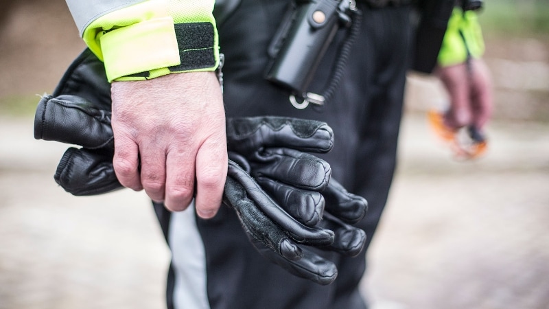 Motoragent houdt eigen handschoenen in de hand