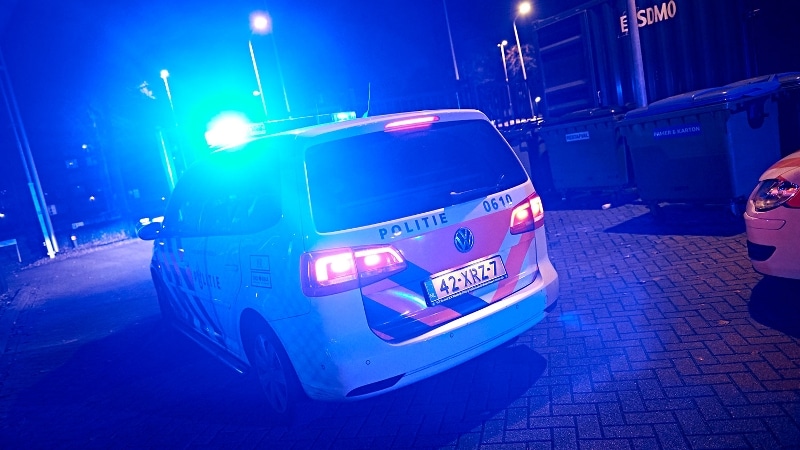 Wegrijdende politieauto met zwaailicht in nacht